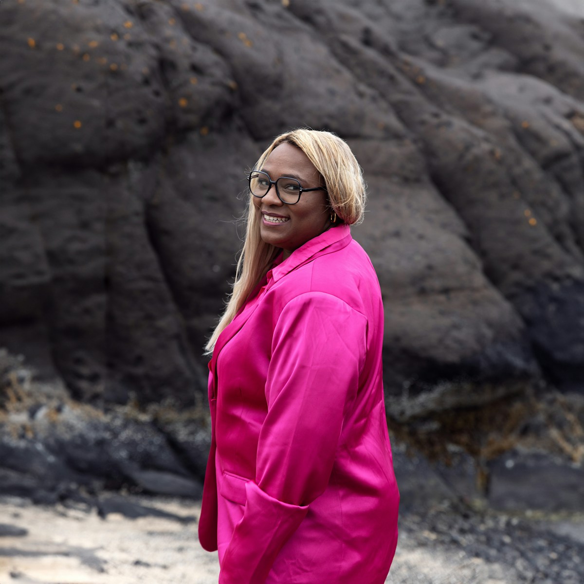 a woman in a pink jacket standing on a beach
