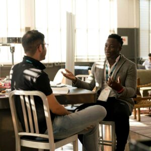 Two men having a casual discussion in a bright indoor setting, highlighting mentorship.